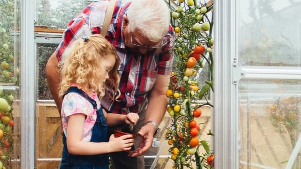 Old man looking at plants with young child